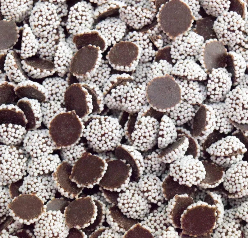 Chocolate nonpareils with white candy sprinkles, bulk chocolate candy closeup