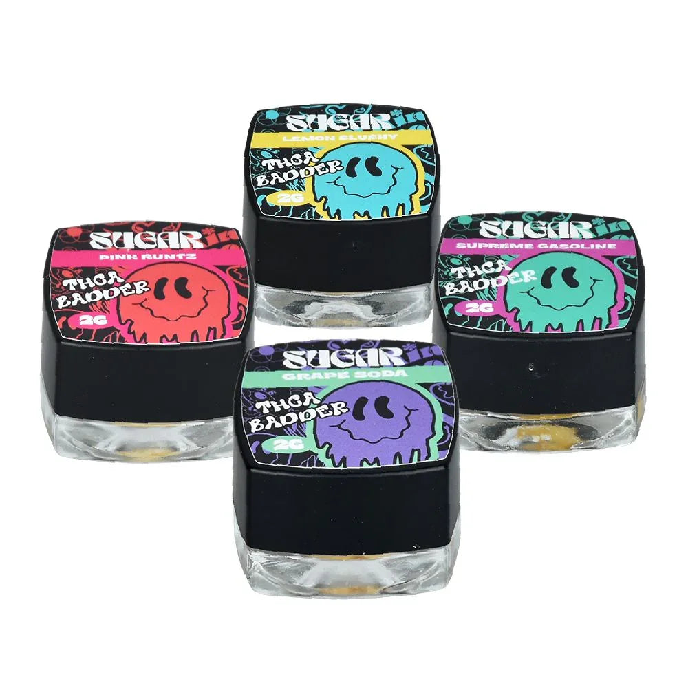 A small glass jar with a black lid, labeled "Trippy Sugar THCa Badder 2G | 5-Pack" by Trippy Sugar, features blue and yellow graphics and contains yellow, crumbly hemp concentrate ideal for dabbing.