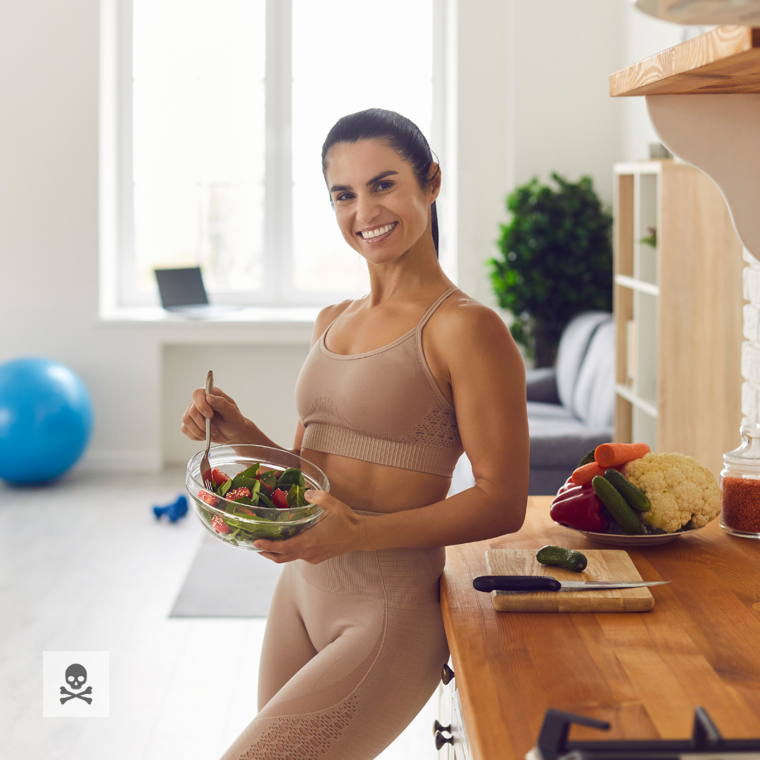 Woman holding a salad in a kitchen with healthy food on the counter