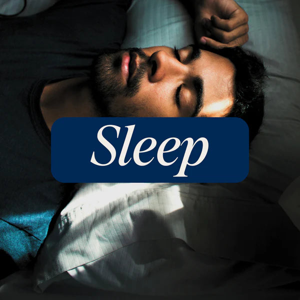 A bearded man sleeps peacefully on his back in bed as sunlight softly lights his face. The word "Sleep" appears boldly on a blue rectangle, suggesting the restful effects of WYLD 2:1 THC/CBN SLEEP Gummies by WYLD.