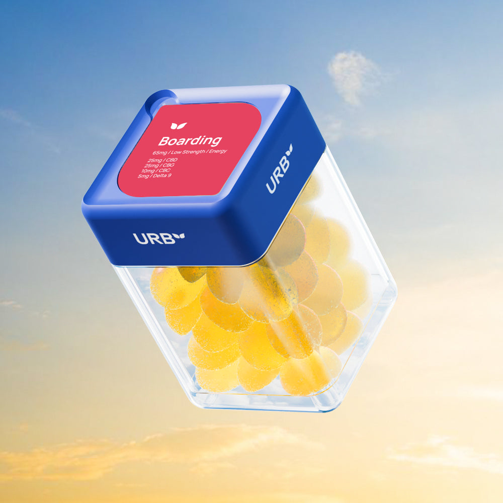 A clear container labeled "Urb Boarding Skybites 65MG Gummies (30ct.)" with a blue lid holds yellow Delta 9 THC gummies, floating against a bright sky with soft clouds and sunlight.