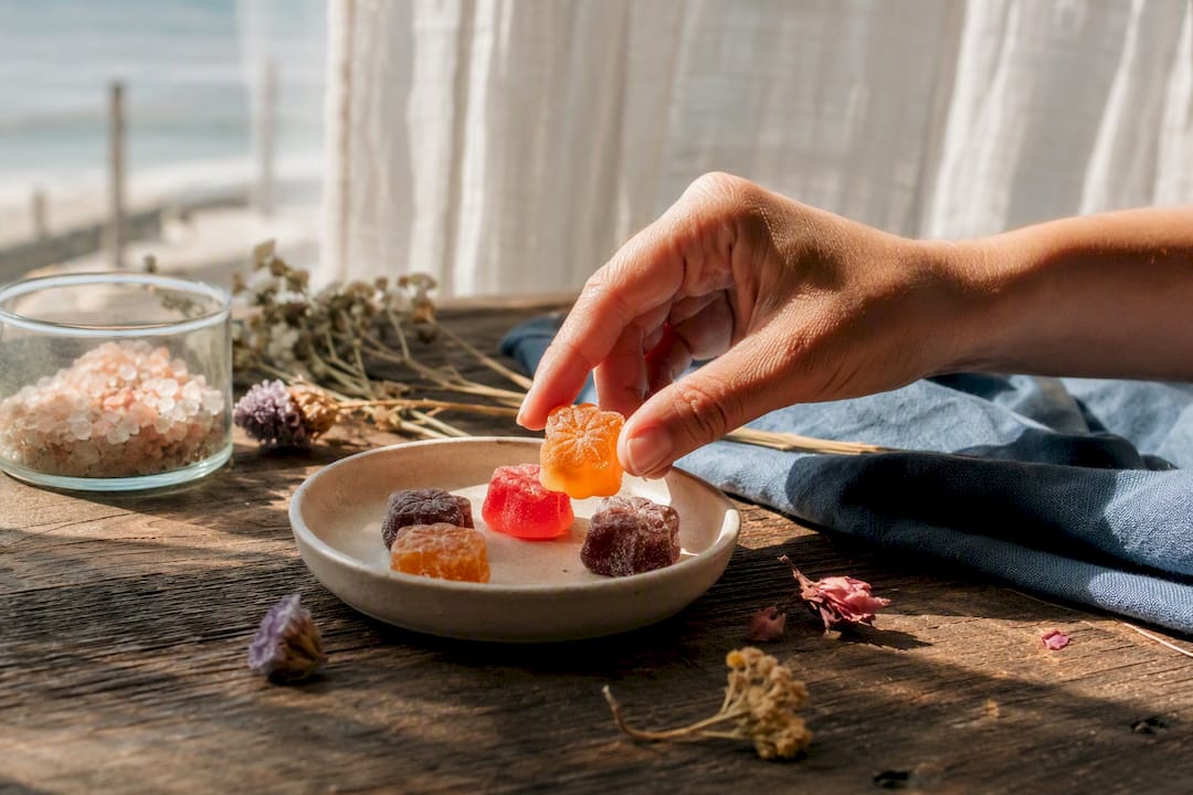 Hand picking lion's mane gummies on wooden surface