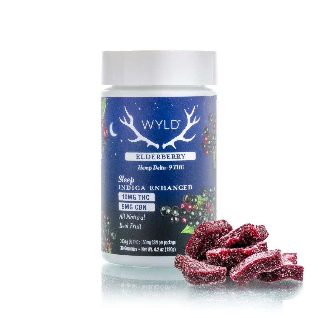 A bearded man sleeps peacefully on his back in bed as sunlight softly lights his face. The word "Sleep" appears boldly on a blue rectangle, suggesting the restful effects of WYLD 2:1 THC/CBN SLEEP Gummies by WYLD.