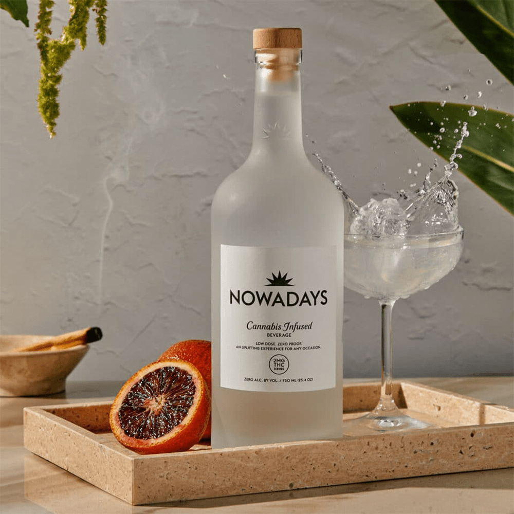 Bottle of 'Nowadays' cannabis-infused beverage on a tray with a glass and fruit.