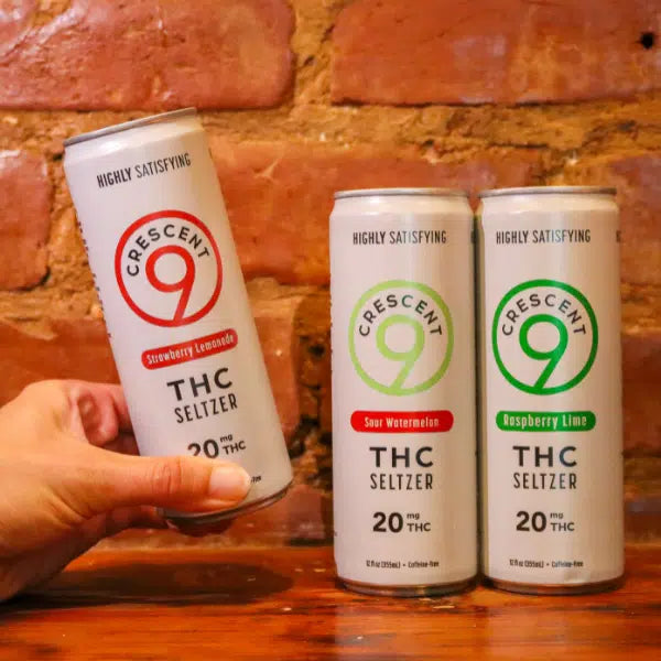 Three cans of Crescent Canna’s Crescent 9 THC Seltzer 20mg in Raspberry Lime, Strawberry Lemonade, and Sour Watermelon. Each sugar-free can contains 20 mg hemp-derived THC and is labeled Highly Satisfying.