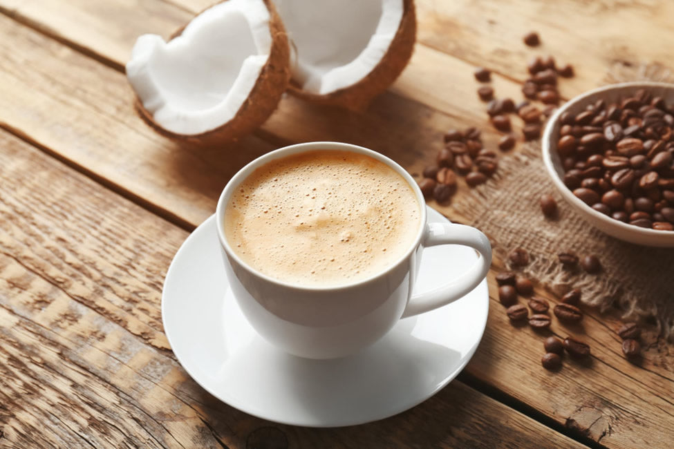 Cup of coffee with coconut halves and coffee beans on a wooden surface